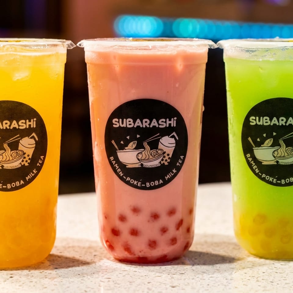 Three colorful Subarashi boba teas: yellow, pink with red pearls, and green with yellow pearls.